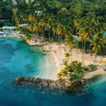 Entdecken Sie die idyllische Küstenlandschaft mit Palmen, klarem Wasser und Yachten, ideal für das perfekte Urlaubs- oder Segelabenteuer.